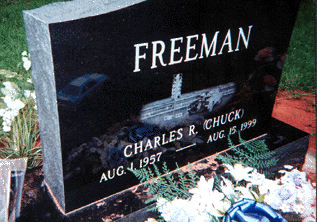 The car on the headstone is the race car Chuck built himself, circa 1990-it's set on a dragstrip with the tree next to it, and the stands behind it.jpg